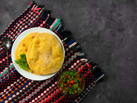 Homemade corn flatbread cilantro green tomato salsa authentic textile. Handmade mexican tortilla vegetable salad.Traditional Indian Punjabi Makki ki roti bread plate top view Wheat flour dough cuisineの写真素材