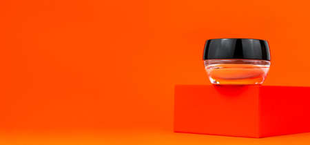 Cosmetic tonal foundation glass jar mockup on geometrical podium orange background. Balancing makeup product Smooth BB liquid cream facial skin. Skintone correction. Modern minimal presentation Bannerの写真素材