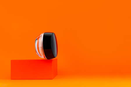 Cosmetic face cream tonal foundation glass jar mockup geometrical podium orange background. Balancing makeup product packaging Smooth BB liquid facial skin. Skintone correction. Modern minimal contentの写真素材