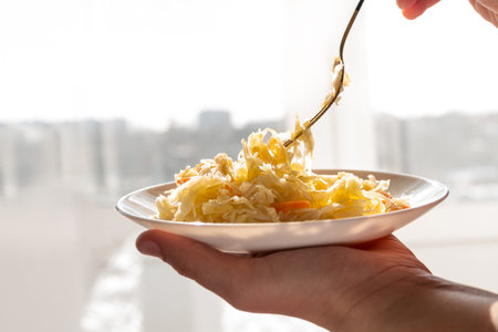 Sauerkraut with vegetable oil in rays of daylight. National european dish Pickled cabbage carrot...