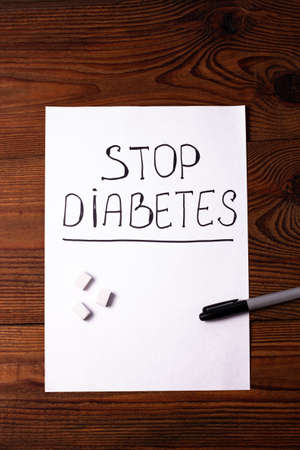 Stop Diabetes sign on a white paper sheet with sugar cubes on wooden background, World diabetes day November 14. Prevent disease before it begins,detection diagnosis, clinical researches,patients listの写真素材