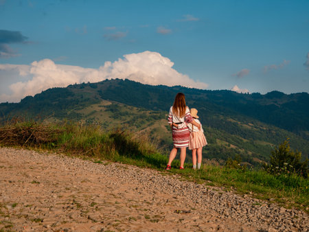 Ukrainian women in authentic costumes Mother and daughter in embroidered shirts standing on beautiful Carpathian Mountains peak scenic view. Independence day of Ukraine Zakarpattya Local travel Europeの写真素材
