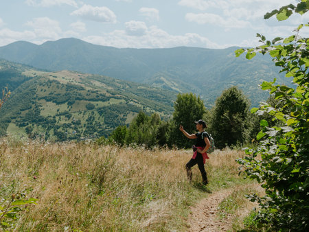 Traveler hiker millennial woman with smartphone backpack in Carpathian mountains summit Ukraine, Europe Girl backpacker taking picture of scenic landscape Active Lifestyle Solo Travel extreme activityの写真素材