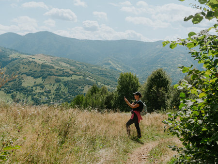 Traveler hiker millennial woman with smartphone backpack in Carpathian mountains summit Ukraine, Europe Girl backpacker taking picture of scenic landscape Active Lifestyle Solo Travel extreme activityの写真素材