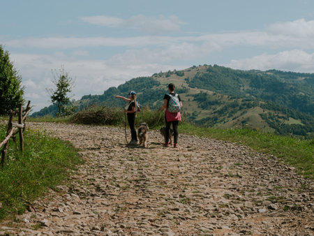 Family walk in Zakarpattya village Carpathian mountains view Ukraine Europe Scenic landscape green trees pets sunny day. Eco Local countryside tourism. Mother and daughter with dogs hiking Cottagecoreの写真素材