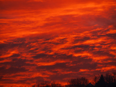 Sunset in the mountains with orange red sky and clouds. Winter Carpathian Mountains view cloudscape. Pine fir tree forest in Carpathians Scenic wood landscape Village in Transcarpathia Ukraine, Europeの写真素材
