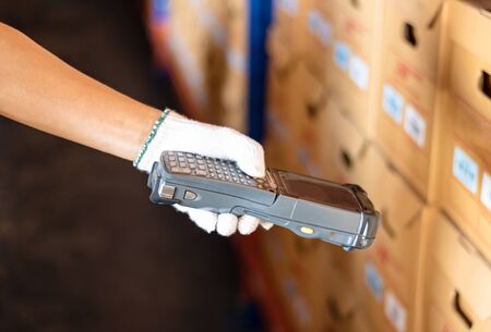 Staff wearing white gloves holding a barcode reader. the product has a sticker using modern technology to read values. Makes business and warehouse management convenient and easy.の写真素材