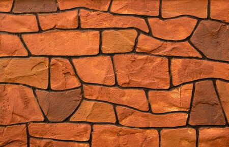 Texture of brown and black stone blocks closeup. Old brown bricks. The background wall has a beautiful pattern. The dark color of the surface makes the fence strong.の写真素材