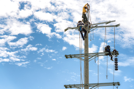 Three man are installing electric pole  and the blue skyの写真素材