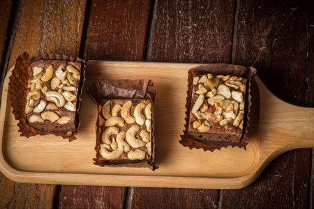 Chocolate Cake There is a sprinkle of nuts on a wooden plateの写真素材
