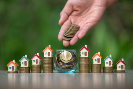 Businessman and accountant is about to put coins in a glass jar. The house is placed on a coin...