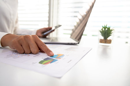 A business woman sitting in front of a laptop in the office.Data analysis concept from summary graph...