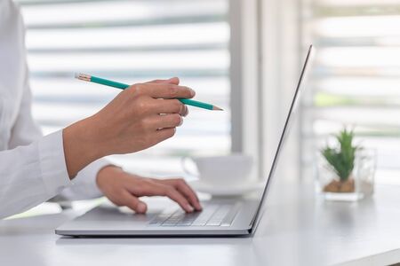 A business person or accountant working in an office.The laptop is on the table. A business person resting his hand on a laptop And use the pencil to show the laptop screen Functional analytical.の写真素材