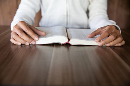 A young woman sat and studied the scriptures laid on a wooden table. The educational concept of the...