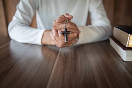 A cross in the hands of a young woman blessing on the scriptures from God with the power and power of holiness, which brings luck and the power of religion, faith, worship, Christian thought.の写真素材