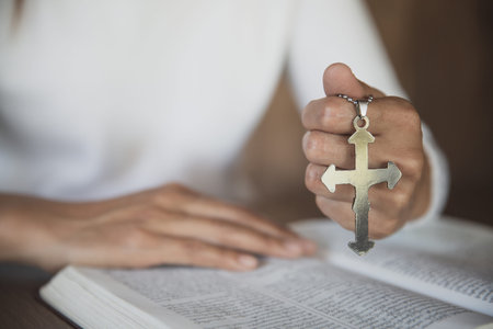 A girl sitting and studying the scriptures. The other hand is holding a cross. Christian education...