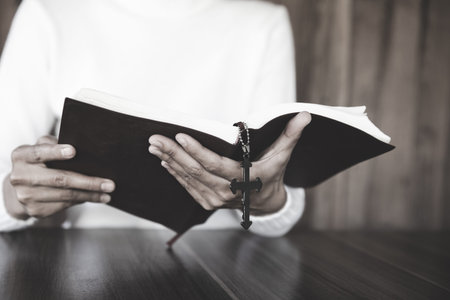 A girl sitting and studying the scriptures. The other hand is holding a cross. Christian education...
