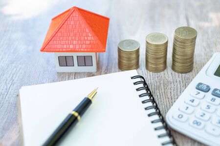 A coin in a hemp bag placed near Orange roof house Money saving ideas for buying a home or loan for real estate investment planning And concepts during the saving of funds may be at risk.の写真素材
