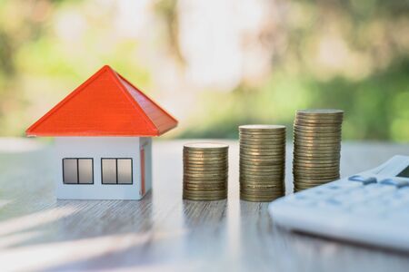 A coin in a hemp bag placed near Orange roof house Money saving ideas for buying a home or loan for real estate investment planning And concepts during the saving of funds may be at risk.の写真素材