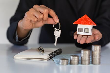 Orange roof house in the hands of businessmen, home insurance concept Property protection. Businessmen protect orange houses.Protecting the home of the sales representative.With text input area.の写真素材