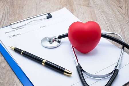 Red heart medical stethoscope and black pen Put on the doctor's charging plate.Health examination concept Health insurance. Medical health. Taking care of yourself as ordered by a doctor.Close up.の写真素材
