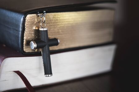 The crucifix was placed near the Bible. The concept of prayer, prayer for salvation from suffering, the religion of Christ Roman Catholic gods, heavenly gods.の写真素材