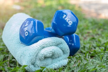 Fitness equipment - Dumbbells, towels placed on the grass The concept of healthy love through exercise Breathe in the natural atmosphere in the morning.の写真素材