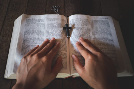 With a girl sitting and studying the Bible The other hand is put on the Bible. The educational...