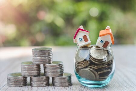 A house on a coin in a glass bottle The coins are stacked into triangular bases. A natural green background that saves money and financial investment ideas for future retirement age homes.の写真素材