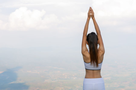 Women exercising or yoga In a gesture of arms straight up And there is a dumbbell nearby Breathe in the natural air Concepts of meditation, calmness, relaxation, sports and recreation.の写真素材