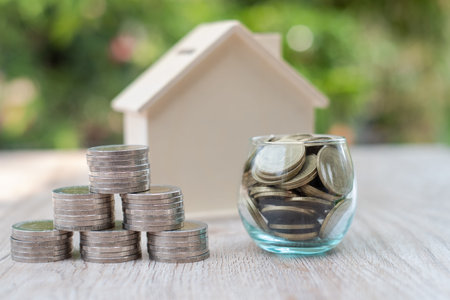 A coin in a glass bottle Coin ladders and wooden houses Concept of saving money and investment...