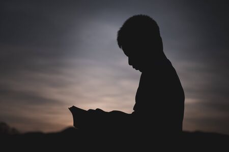 A boy who studies the scriptures Sunrise or sunset background. The educational concept of Christian Tripitaka that is open and praying to God.の写真素材