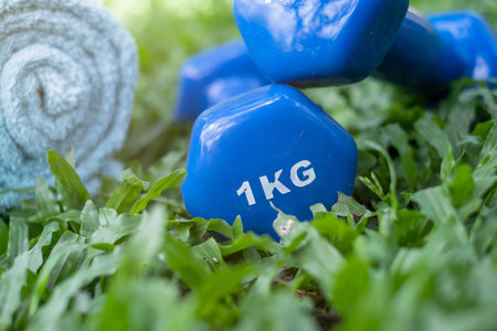 Fitness equipment - close-up shots of dumbbells, towels placed on the grass, the concept of love for...
