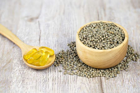 Cannabis seeds in a wooden cup And extracted hemp oil is packed in capsules There is a blank space for the message. Natural herbal extracts.の写真素材