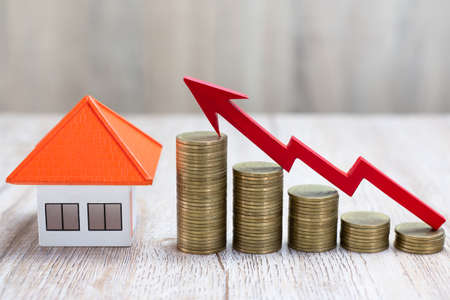 The red arrow on the coin pile And orange roof houses Real estate growth concept, financial planning, account management and success chart. Saving money to buy a house.の写真素材