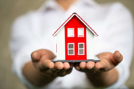Red roof house on hand, sales representative. Sign contracts, signatures on official documents, customer partners, customers who purchase products or sign contracts, home trading ideas.の写真素材