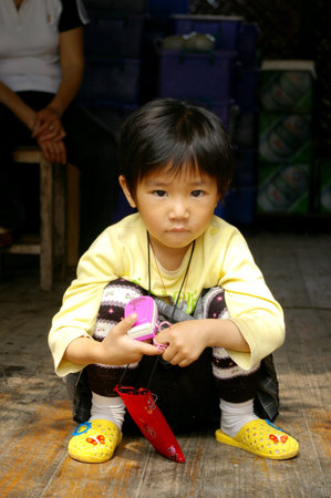 CHINA - MAY 16, A traditional Chinese young girl is sitting outside a shop on Yangshuo, China on 16 May, 2010.のeditorial素材