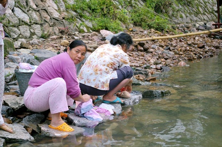 CHINA - MAY 17, Chinese woman is washing clothes along Li River in Yangshuo, China on 17 May, 2010.のeditorial素材
