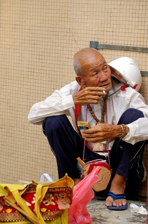 HONG KONG - AUG 1, An old man is sitting along the street and smoking in Hong Kong on 1 August, 2009.のeditorial素材
