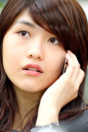 Asian woman talking on phone with curious faceの写真素材