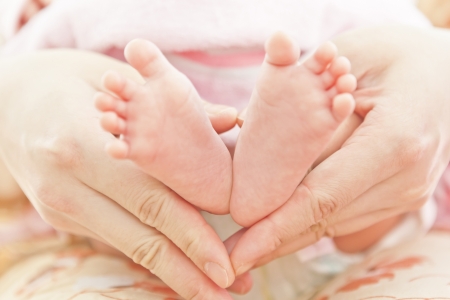 Feet of newborn baby in mothers hands の写真素材