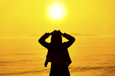 Silhouette of woman thinking on the beach at sunsetの写真素材