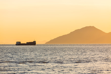Cargo ship sailing at sunsetの写真素材