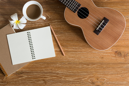 image of ukulele , notebook and coffee on wooden table with copy space.の写真素材