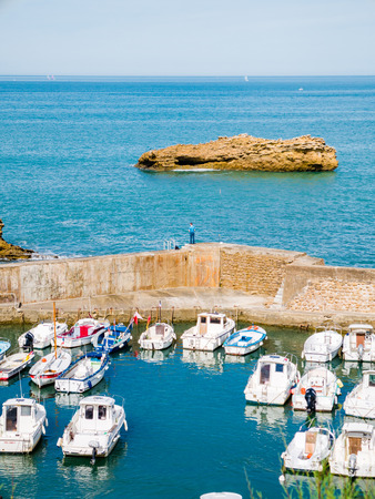 The walls surrounding the Port des Pecheurs at Biarritz, Basque country. A man is standing on the wall, while boats dock at port.の写真素材