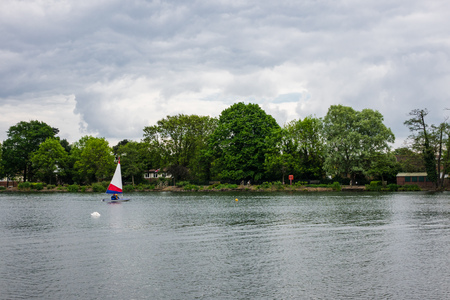 Landscape view of South Norwood lake where people can be seen pracitcing water sport activities such as sailingの写真素材