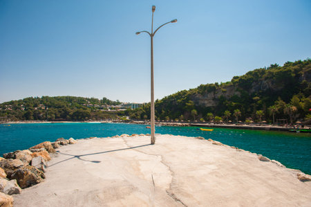 a pole with a lantern on the beach backlit by the seaの写真素材
