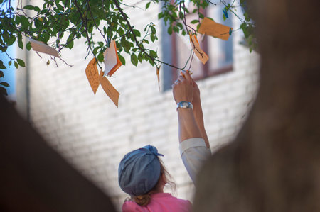 hang notes with wishes on a tree, notes of orange color.