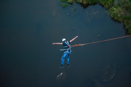 Extreme jump from the bridge. The man jumps surprisingly quickly in bungee jumping at Sky Park explores extreme fun. Bungee in the canyonの写真素材