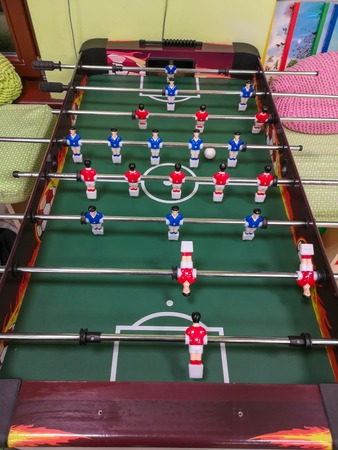 Friends having fun together playing foosball. Colleagues playing table football on break. Office people enjoying table soccer game. Close up of table football kicker gameの写真素材